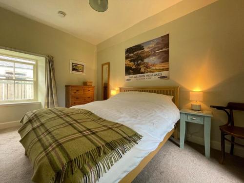 a bedroom with a large bed and a window at Old Manse Cottage in Auchterneed