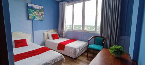 a blue room with two beds and a chair and a window at Phuong Thuy Hotel Thu Duc near QL13 in Ho Chi Minh City