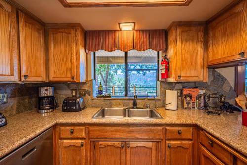 a kitchen with wooden cabinets and a sink and a window at Mountain View Playhouse Near Yosemite & Bass Lake in Oakhurst