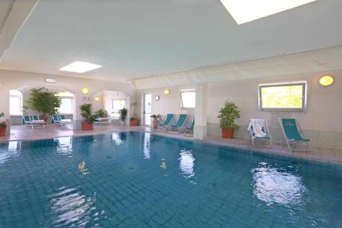 a large swimming pool in a hotel with blue chairs at Hotel Terme Villa Teresa in Ischia