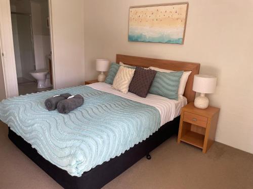 a bed with two stuffed animals laying on it at Seachange Apartments Merimbula in Merimbula