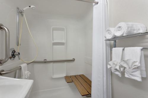 a bathroom with a shower and a sink and towels at Microtel Inn By Wyndham Louisville East in Louisville