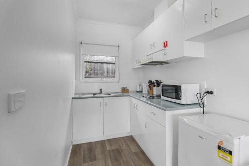 a white kitchen with a sink and a microwave at Mibnb Geelong CBD in Geelong