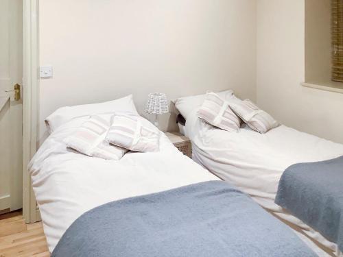 two beds in a room with white sheets and pillows at Bramble Cottage in Ingoldisthorpe