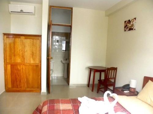 a bedroom with a bed and a table and a door at Hotel Jose Antonios Inn in Puerto Maldonado