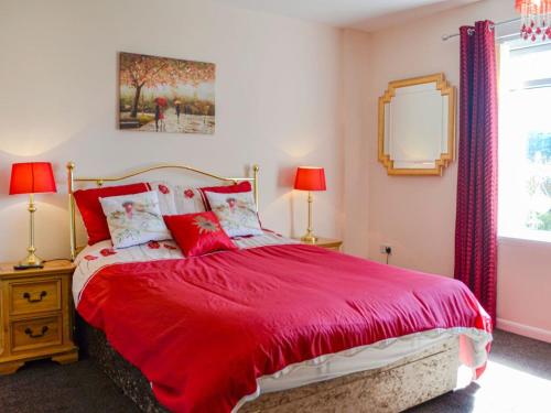 a bedroom with a red bed with two lamps and a mirror at Kinvara in Stranraer