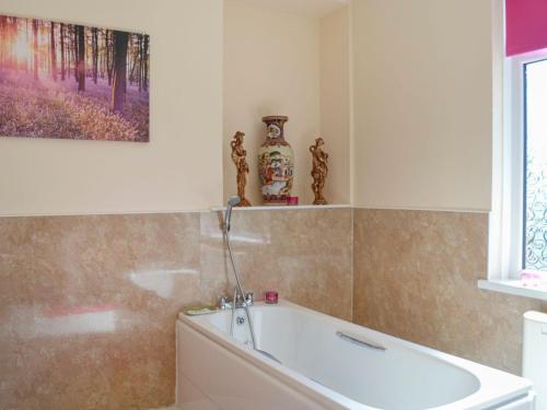 a bath tub in a bathroom with a painting on the wall at Kinvara in Stranraer