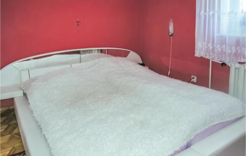 a bedroom with a white bed with a red wall at Beautiful Home In Dzwierzuty With Kitchen in Dźwierzuty