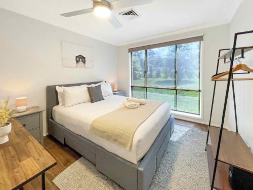 a bedroom with a bed and a large window at Nottage Cottage in Branxton