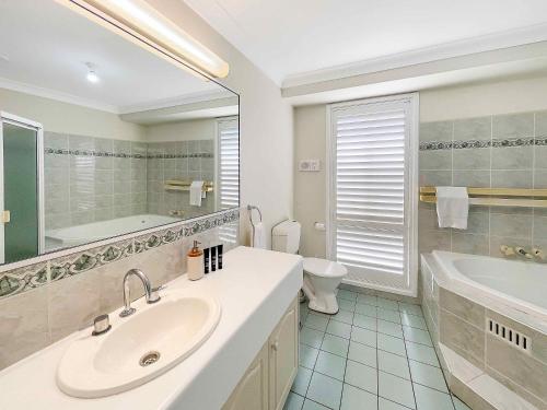 a bathroom with a sink and a tub and a toilet at Nottage Cottage in Branxton