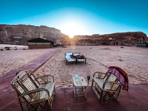 grupa krzeseł i stół na pustyni w obiekcie Bedouin Tours Camp w mieście Wadi Rum