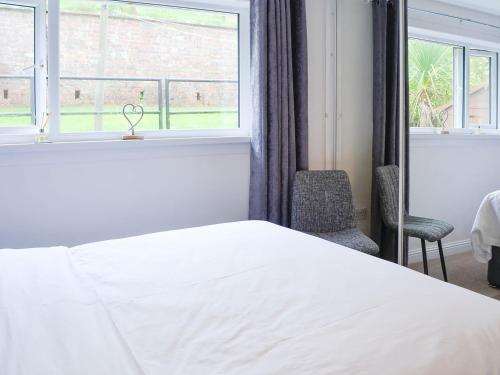 a bedroom with a white bed and a window at Thistle Cottage in Portpatrick
