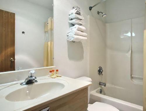 ein weißes Bad mit einem Waschbecken und einer Dusche in der Unterkunft Travelodge by Wyndham Waukegan Gurnee in Waukegan