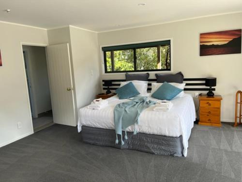 a bedroom with a large white bed with blue pillows at Treetops Cottage at the Castle in Whitianga