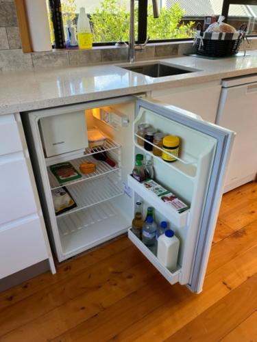 a refrigerator with its door open in a kitchen at Treetops Cottage at the Castle in Whitianga