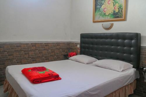 uma cama com uma cabeceira preta e um saco vermelho em Wisma Vandera Syariah Garut Mitra RedDoorz em Garut