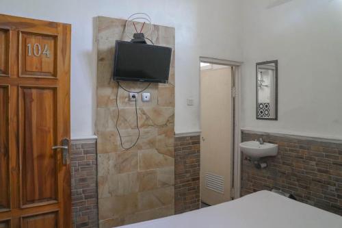 uma casa de banho com um lavatório e uma televisão na parede em Wisma Vandera Syariah Garut Mitra RedDoorz em Garut