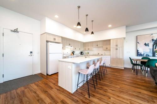 a kitchen with white cabinets and a bar with stools at Exotic,LUSH,Rainforest,CR,Suite,King,U/G,Wifi in Edmonton