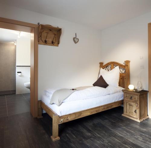 a bedroom with a bed with white sheets and a table at MyApart Jochberg in Jochberg