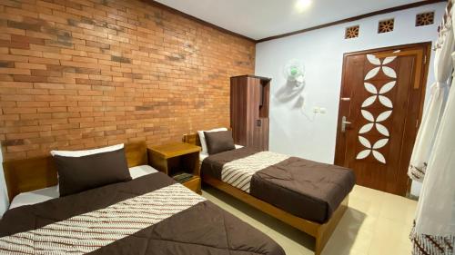 una camera con due letti e un muro di mattoni di Homestay Candi Pawon Murtakim Syariah a Mendut