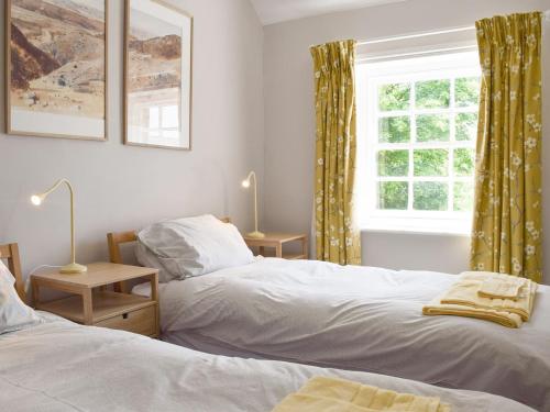 1 dormitorio con 2 camas y ventana en Cooks Cottage, en Knossington