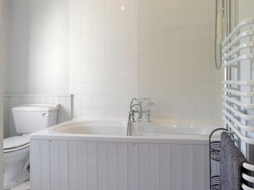 a white bathroom with a tub and a toilet at Cooks Cottage in Knossington