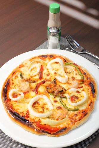 a pizza on a white plate on a table at ON Hotel Phuket - SHA in Karon Beach
