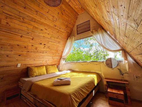 a bedroom with a bed in a wooden room with a window at Nấp ở TEEPEE homestay in Da Lat