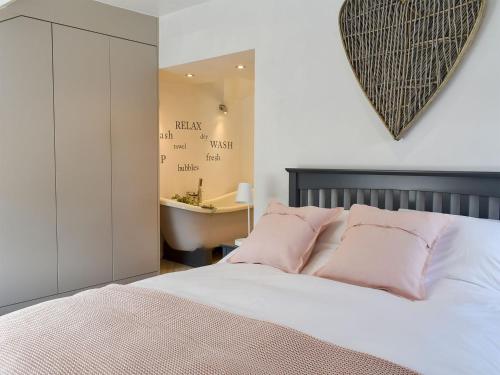 1 dormitorio con 1 cama con almohadas rosas y un corazón en la pared en Little Plumtree, en Addingham