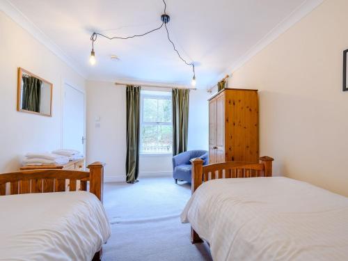 a bedroom with two beds and a blue chair at Great Whaup in Culter