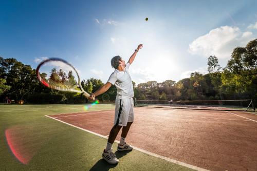 un hombre sosteniendo una raqueta de tenis en una pista de tenis en Amareclub Rocca Dorada en Santa Margherita di Pula