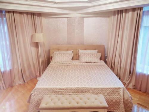 a bedroom with a large bed in a room with windows at Stunning new design apartment next to park in Chişinău