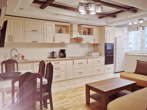 a kitchen with white cabinets and a table and a dining room at Stunning new design apartment next to park in Chişinău