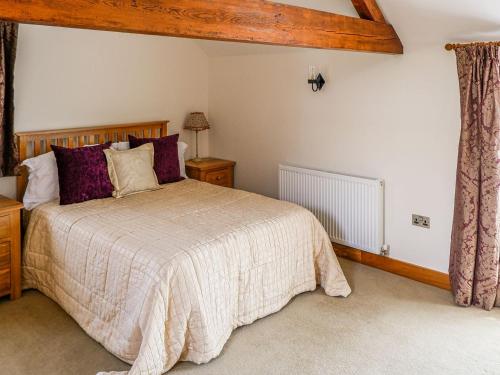 a bedroom with a large bed with purple pillows at The Milking Parlour in Tutbury