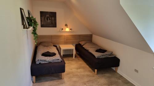 a attic room with two beds and a table at Værelse, spiseområde, tv-stue og eget bad på landet in Kværndrup