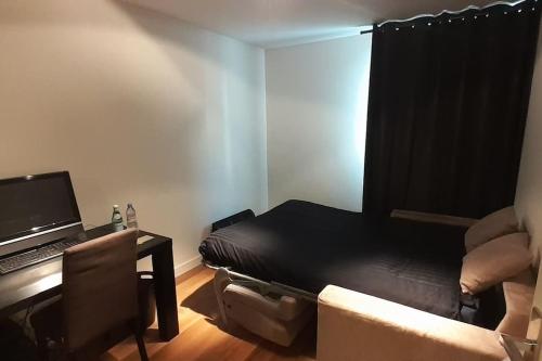 Cette chambre comprend un lit et un bureau avec un ordinateur portable. dans l'établissement Appt centre ville "Parc Olympe de Gouges" avec garage, à Annemasse