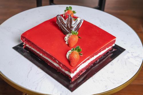 a red cake with strawberries on top on a white plate at Pearl Grand By Rathna in Colombo