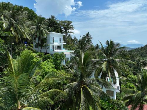 a white house on a hill with palm trees at Villa Melo in Chaweng Noi Beach