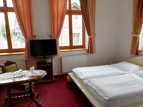 a bedroom with a bed and a table and a tv at Pension sv. Florian in Hlučín