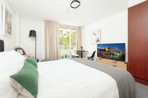 a bedroom with a white bed and a flat screen tv at MP303 - Studio Apartment, Military Road, Cremorne in Sydney