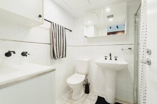 a white bathroom with a toilet and a sink at MP303 - Studio Apartment, Military Road, Cremorne in Sydney