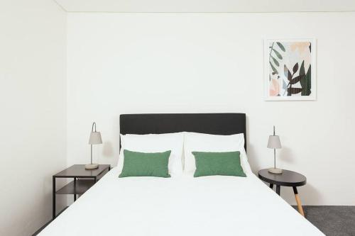 a white bedroom with a white bed with green pillows at MP303 - Studio Apartment, Military Road, Cremorne in Sydney