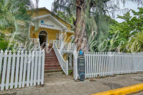 uma casa amarela com uma cerca branca e uma árvore em Looking Good Surf House San Juan del Sur em San Juan del Sur