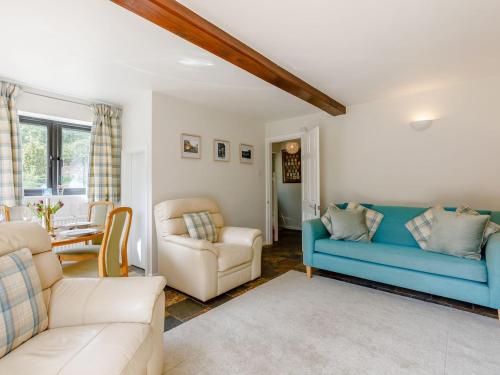 a living room with a blue couch and chairs at Stocks Cottage in Blockley