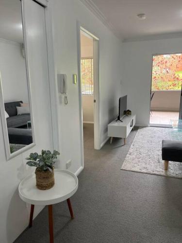 a white living room with a table and a tv at 2 bedroom modern coastal retreat in Kiama