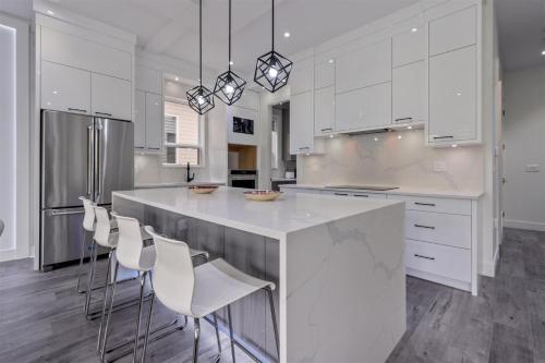 a kitchen with white cabinets and a large island with chairs at Charming, Cheerful, Exquisite 4 BR house, free wifi, free parking, free cancelation in Langley