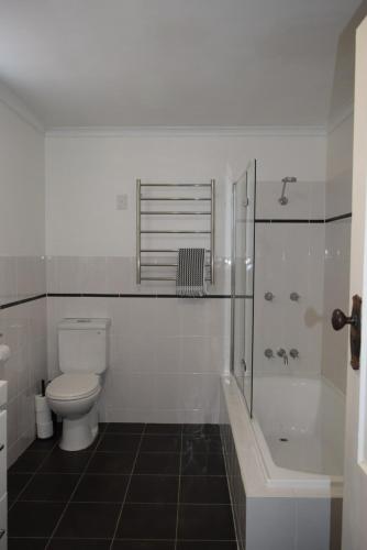 a white bathroom with a toilet and a shower at Fitzroy House - Federation charm near town centre in Cowra