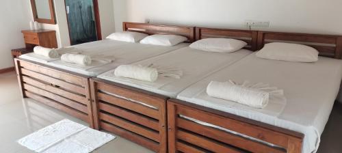 a large wooden bed with white pillows on it at Rajarata Family Resort in Anuradhapura