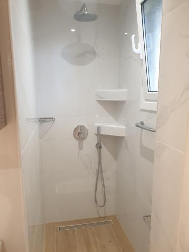 biała łazienka z prysznicem i umywalką w obiekcie Newly Renovated Varkiza Beachside One Bedroom with Large Terrace w Atenach