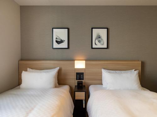 東京にあるベストウェスタンホテルフィーノ東京秋葉原のベッド2台が備わる客室で、壁に2枚の写真が飾られています。